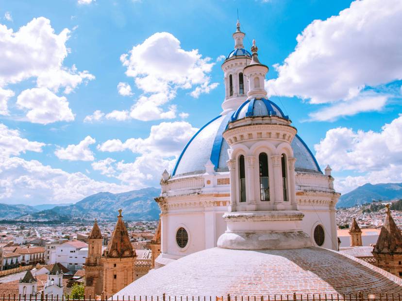 Vista de una cúpula blanca y azul de una iglesia con la ciudad de fondo bajo un cielo claro.