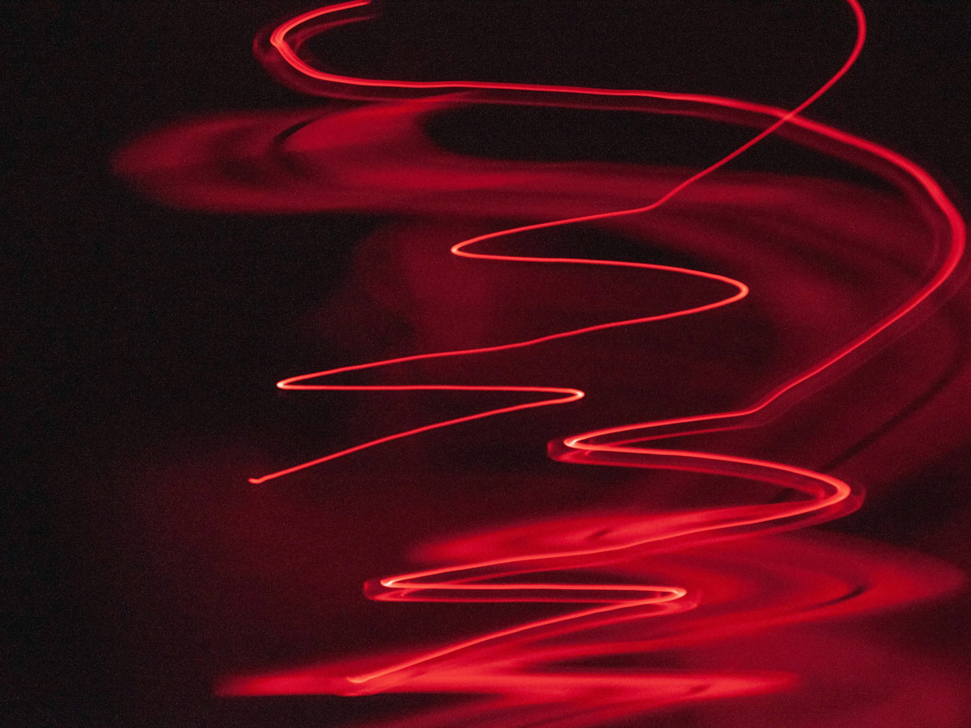 ksenia-7v8jxktqxbk-unsplash-eb32d19c-2b3e-4283-b75e-01328dd81f11 La imagen muestra un patrón de luces rojas que se mueven en una forma ondulada y fluida.
