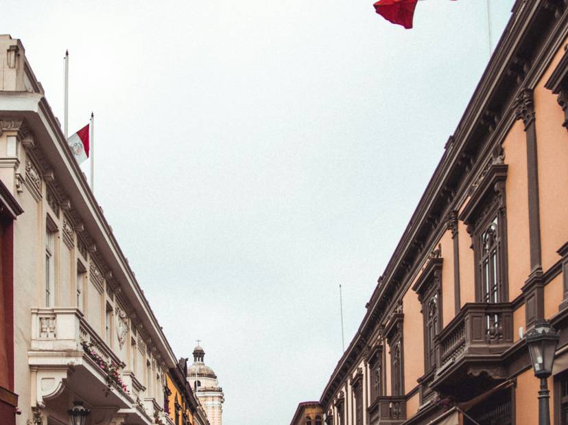 Imagen de una calle peatonal con edificios de estilo colonial y una bandera roja y blanca ondeando.
