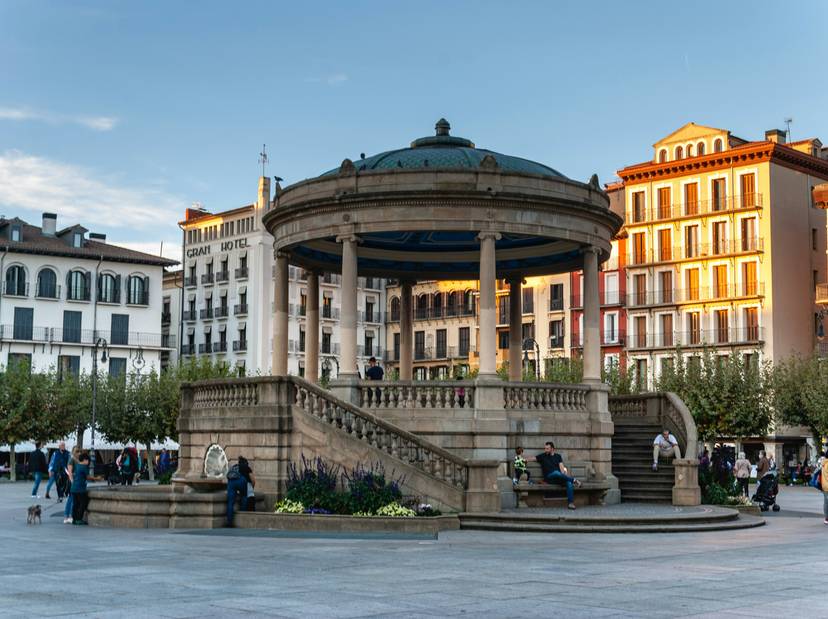 david-vives-b87x69td-k-unsplash Vista de un quiosco de música en una plaza pública con edificios coloridos alrededor y personas disfrutando del ambiente.