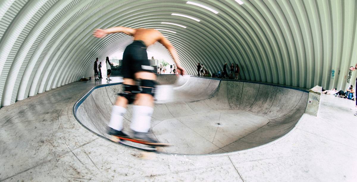 Un skater realiza una maniobra en un bowl dentro de una instalación cubierta.