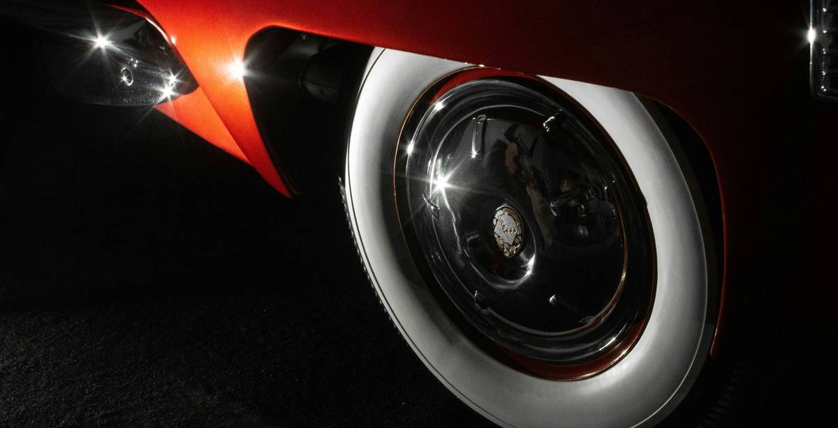 La imagen muestra una rueda de un automóvil clásico con detalles de brillo en la llanta y neumático blanco.