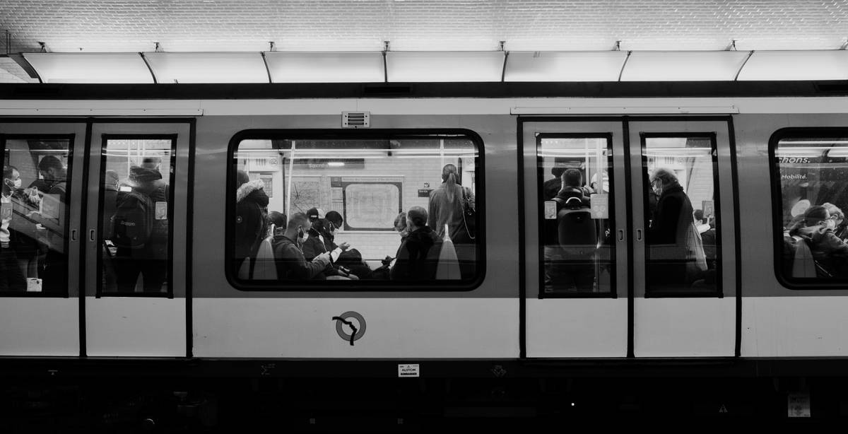 Una estación de metro con pasajeros visibles a través de las ventanas del tren.