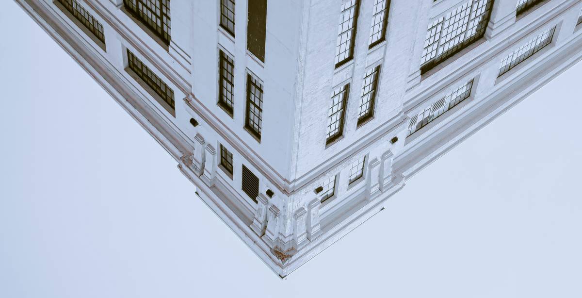 Una esquina de un edificio blanco con ventanas grandes en un fondo claro.