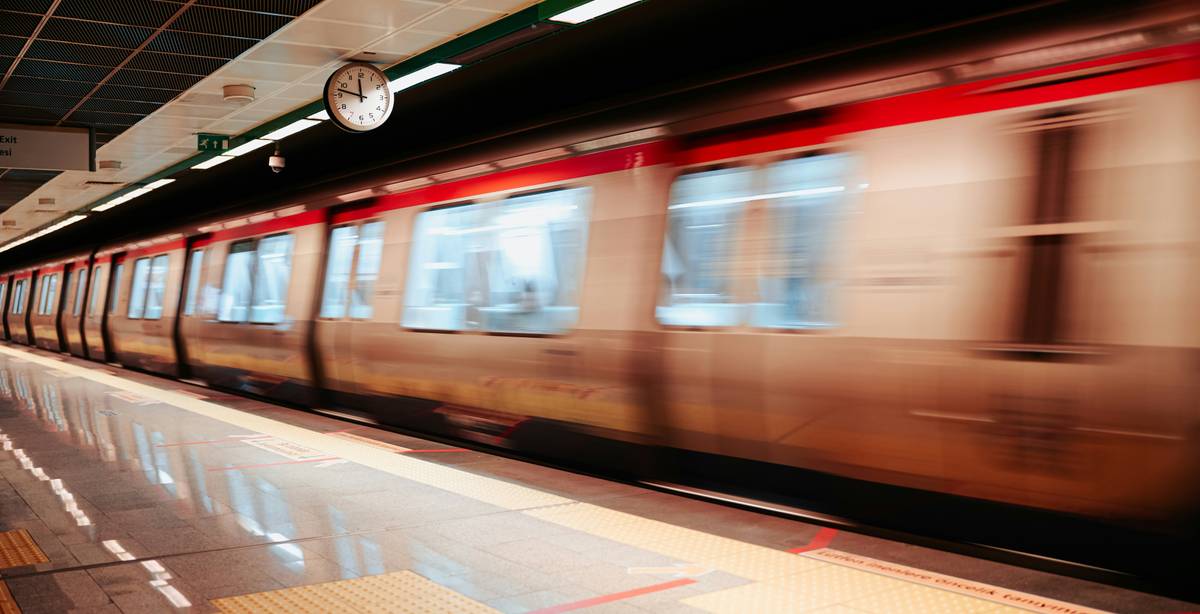 Un tren de metro se mueve rápidamente por una estación subterránea.