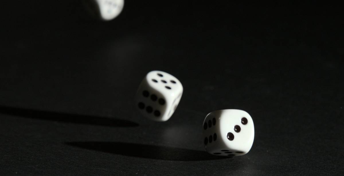 Tres dados blancos en movimiento sobre un fondo oscuro.