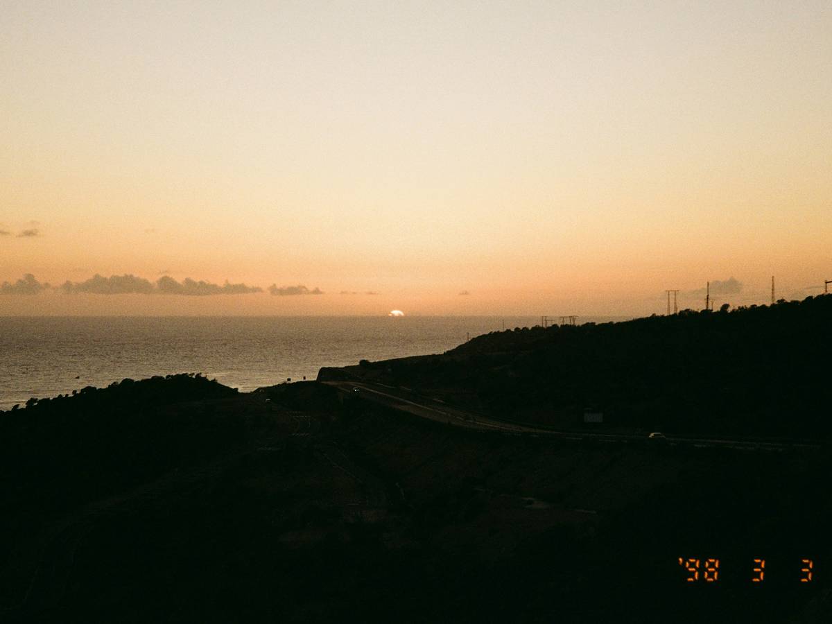 Un hermoso atardecer sobre el mar con montañas en primer plano.