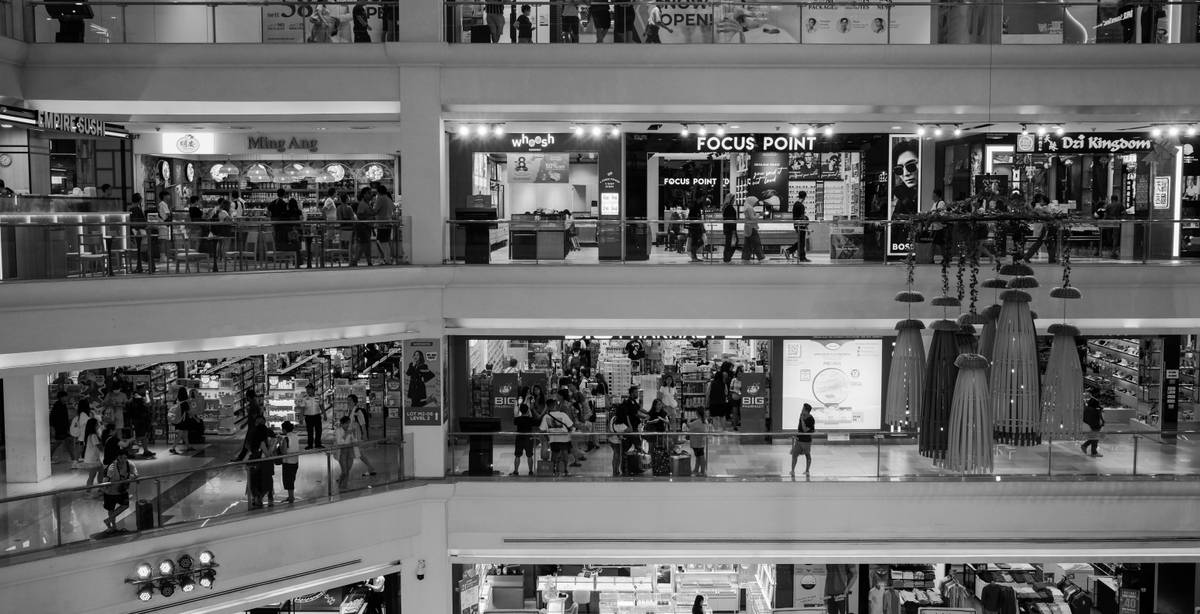 Una vista interior de un centro comercial con diferentes tiendas y personas en movimiento.