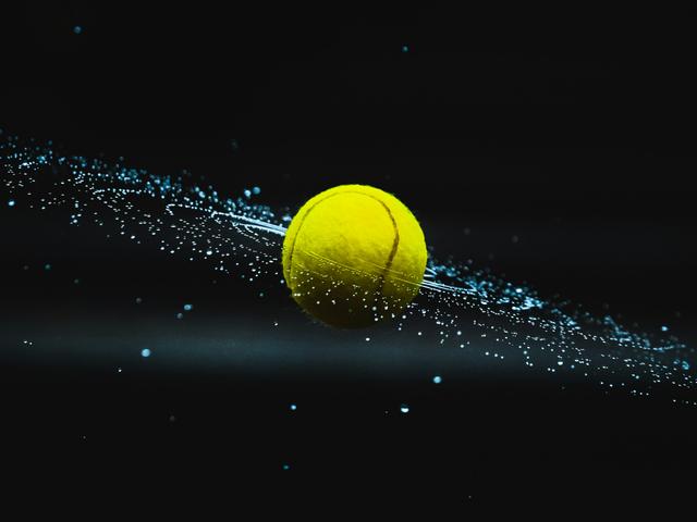 Una pelota de tenis amarilla flota en el espacio rodeada de destellos de luz azul.
