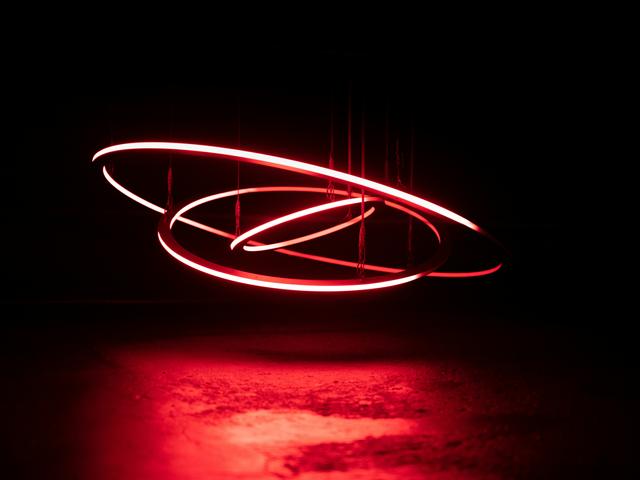Una instalación de luces rojas en un entorno oscuro que parece girar en círculos.
